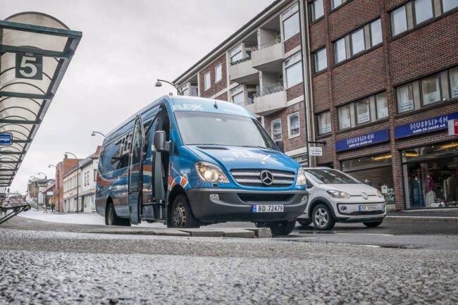 Blue van parked on a city street near apartment buildings.