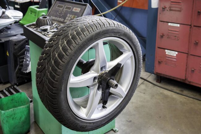 A tire mounted on a wheel balancing machine in a workshop.
