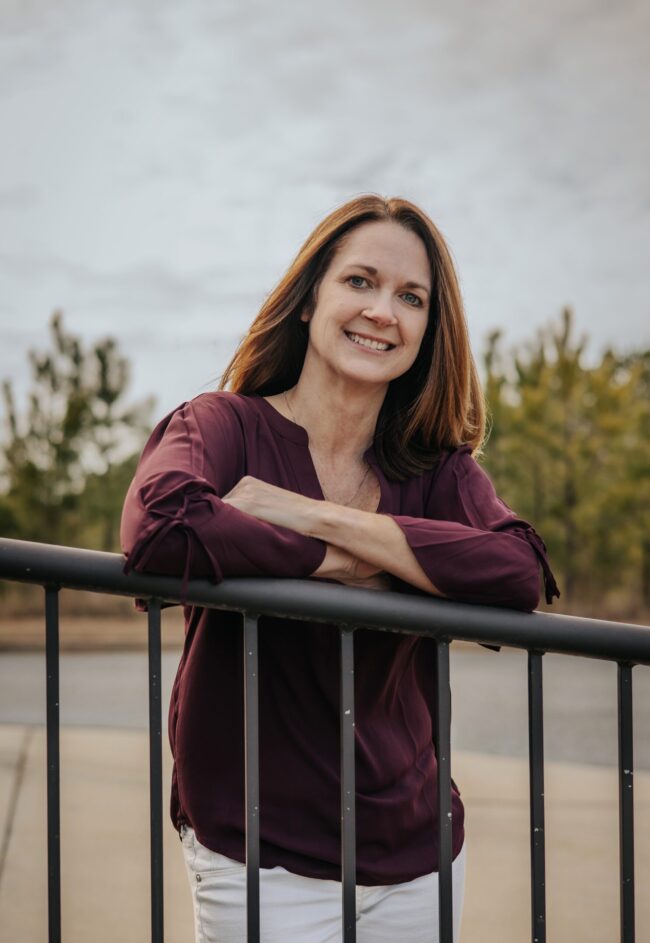 Smiling woman leaning on a railing outdoors.