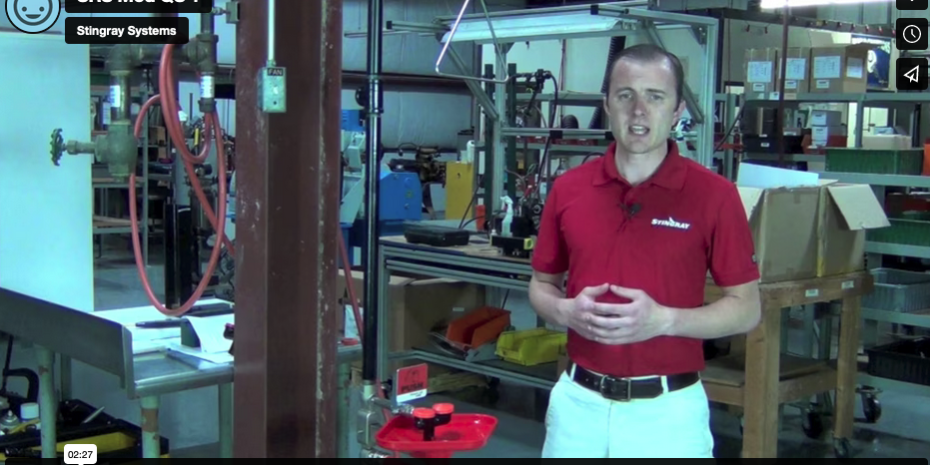 Man in red shirt standing in a workshop with tools and machinery.